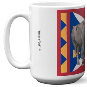 May include: White ceramic mug with a large handle. The mug features a design with a red border, blue and yellow geometric shapes, and a gray animal illustration. The text "Stories of Old" is printed on the side.