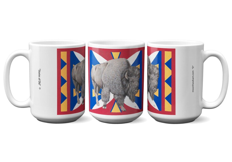May include: White ceramic mug featuring a bison illustration on a red, white, blue, and yellow geometric design. The mug has the text "Stories of Old" and "moonhawkart.com" printed on it.