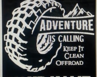 May include: Black and white graphic design with a tire, mountains, and the text "Adventure is calling Keep it clean offroad". The text "Your Name" is at the bottom of the design.