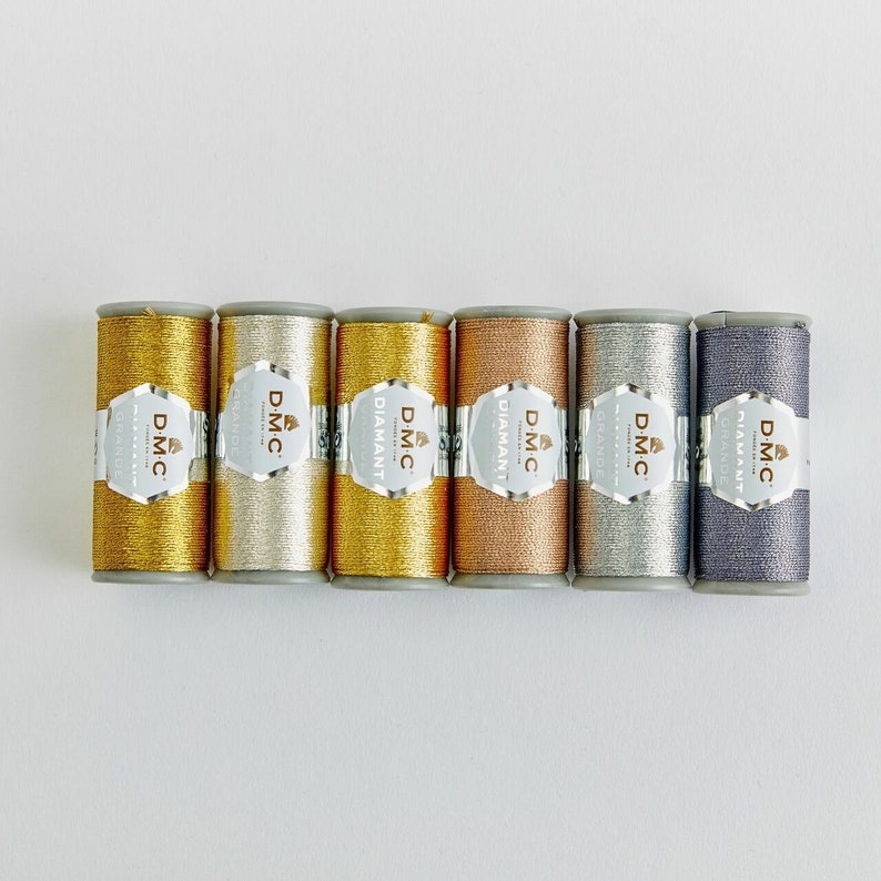 May include: Six spools of DMC Diamant embroidery thread in gold, silver, copper, light gray, and dark gray.