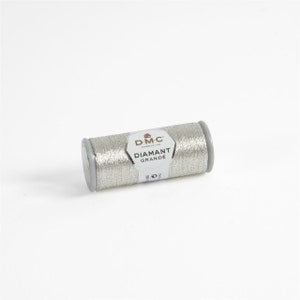 May include: A silver spool of DMC Diamant Grande embroidery thread. The spool is labeled with the DMC logo and the text "Diamant Grande".