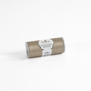 May include: A spool of gold metallic thread labeled "DMC Diamant Grande" for embroidery and crafting.
