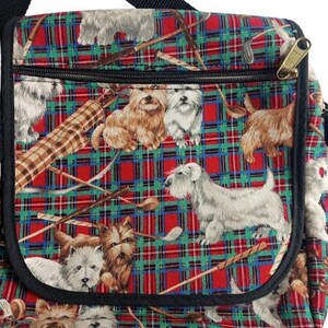 May include: A shoulder bag with a black strap and zipper, featuring a red, green, and blue plaid pattern. The bag is decorated with illustrations of various dog breeds and golf clubs.