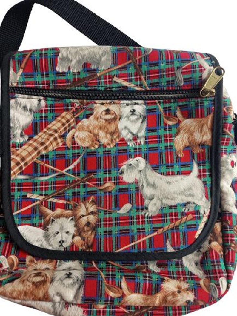 May include: A shoulder bag with a black strap and zipper, featuring a red, green, and blue plaid pattern. The bag is decorated with illustrations of various dog breeds and golf clubs.