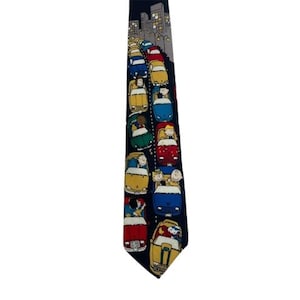 May include: A navy blue tie with a repeating pattern of Peanuts characters riding in cars. The cars are yellow, red, blue, and green. The characters are all smiling and waving. The tie is a great way to show your love for the Peanuts gang.