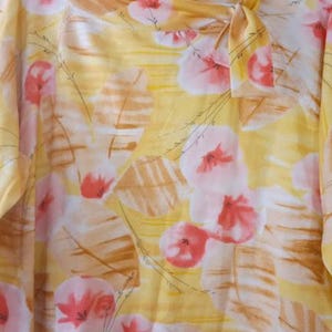 Peut inclure: Chemisier jaune avec un motif floral de fleurs roses et blanches et de formes en forme de feuilles marron. Le chemisier a une encolure ronde avec un n&oelig;ud. Le tissu semble l&eacute;ger et fluide.