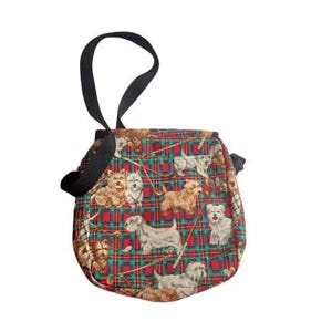 May include: A small, round bag with a black handle. The bag features a red and green plaid pattern with various dog breeds printed on it. The bag is made of fabric and has a simple design.