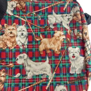 May include: A square bag with a red, green, and blue plaid pattern. The pattern is filled with illustrations of dogs and golf clubs. The bag has a black strap.