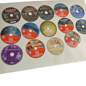 Może przedstawiać: Kolekcja 14 dysków z grami komputerowymi, z tytułami takimi jak "Legends", "Mystery Chronicles", "Dark Tales", "Escape", "Mystic Diary", "Sherlock Holmes" i "Ravenhearst".