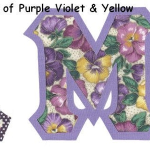May include: Two fabric letters, A and M, with a purple border and a floral pattern of purple, yellow, and white pansies. The letters are on a white background. #84 Pansies Shades of Purple Violet & Yellow