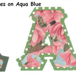 May include: Two green felt letters "A" with a pink rose pattern. The letter on the left has a solid green border. The letter on the right has a white polka dot border.