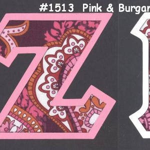 May include: Two fabric letters, Z and K, in a pink and burgundy paisley pattern. The letters are cut out of white paper and have a pink outline.