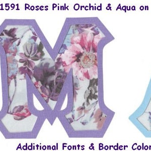 May include: Two fabric letters, "M" and "A", with a floral pattern in shades of pink, purple, and blue. The letters have a light purple and light blue border, respectively. The text "#1591 Roses Pink Orchid & Aqua on Lt Blue BGround" is above the letters. The text "Additional Fonts & Border Colors Available!" is below the letters.