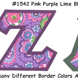 May include: Two fabric letters, Z and A, in a purple and pink paisley pattern with a dark purple and green border. The letters are outlined in a darker shade of purple and green. The text #1542 Pink Purple Lime Blue Paisley is at the top of the image. The text Many Different Border Colors Are Available - UPick is at the bottom of the image.
