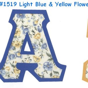May include: Two fabric letters, A and I, with a light blue and yellow floral pattern. The letter A is outlined in blue and the letter I is outlined in orange.