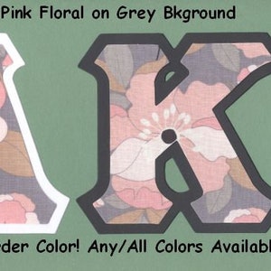May include: Two large letters, A and K, are cut out of a salmon pink floral fabric with a gray background. The letters have white and black borders. The text "#1609 Salmon Pink Floral on Grey Bkground" is at the top of the image. The text "U-Pick Border Color! Any/All Colors Available" is at the bottom of the image.