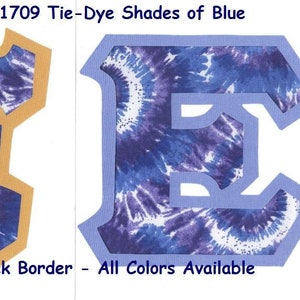 May include: Two tie-dye fabric letters, one "E" and one "I", with a blue and white swirl pattern. The "E" has a light blue border and the "I" has a gold border. The text "#1709 Tie-Dye Shades of Blue" and "U-Pick Border - All Colors Available" is visible below the letters.