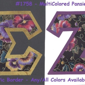 May include: Two fabric letters, a gold "S" and a purple "Z", with a floral pattern of pansies in shades of purple, pink, and yellow on a black background. The letters are outlined in gold and purple, respectively. The text "#1758 - MultiColored Pansies" is above the letters, and "U Pic Border - Any/All Colors Available" is below.
