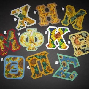 May include: Ten fabric letters with a sunflower pattern. The letters are in white, red, yellow, blue, and green. The letters are numbered 1 through 10.