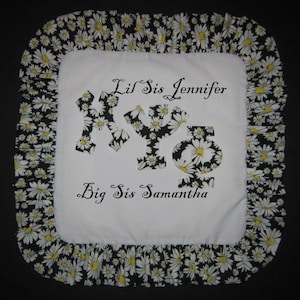 May include: White pillow with black and white daisy print border. The pillow has the text "Lil Sis Jennifer" and "Big Sis Samantha" embroidered on it.