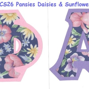 May include: Two letters, a pink "Phi" and a purple "A", are cut out of a blue fabric with a floral pattern. The fabric features pansies, daisies, and sunflowers. The letters are outlined in pink and purple.