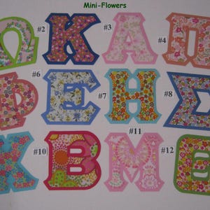 May include: Twelve fabric letters in various colors and patterns, including pink, green, blue, and red. The letters are in a block font style and are numbered 1 through 12. The letters spell out "OKAN ΦΕΗΣ XBMO".