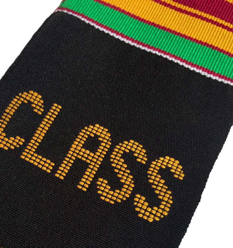 May include: Black graduation stole with gold text reading "CLASS." The stole has a colorful trim of red, green, and gold stripes. The fabric appears to be a textured weave, suitable for a graduation ceremony.
