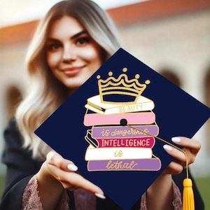 May include: A navy blue graduation cap with a gold crown and a stack of books that say "Beauty is dangerous, Intelligence is lethal".