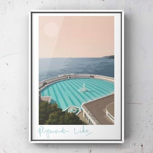 Könnte beinhalten: Gerahmter Kunstdruck mit einer stilisierten Illustration des Plymouth Lido Schwimmbads. Das Kunstwerk zeigt das Schwimmbad mit türkisfarbenem Wasser und einem Brunnen, vor dem Hintergrund des Meeres und eines pfirsichfarbenen Himmels. Der Text "Plymouth Lido" ist in türkisfarbener Schrift geschrieben.