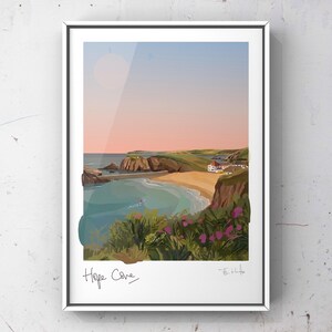 May include: A framed art print featuring a coastal landscape of Hope Cove with a sandy beach, turquoise water, rocky cliffs, and green hills under a soft pink and blue sky. The foreground shows green foliage with pink flowers and the text Hope Cove.
