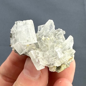 Peut inclure: Un groupe de cristaux de calcite clairs, translucides, avec une base légèrement blanc cassé, opaque. Les cristaux sont nets et bien définis, avec un éclat vitreux.