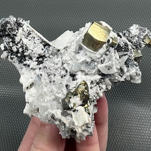 May include: A cluster of white and gray crystals with gold pyrite crystals embedded in the matrix. The crystals are arranged in a random pattern and have a rough, natural texture.
