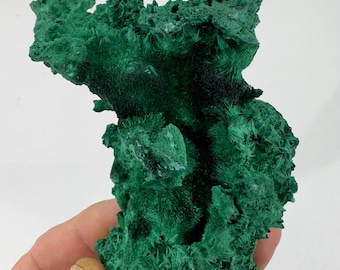 May include: A large, green malachite specimen with a rough, textured surface. The malachite has a deep green color and a crystalline structure.