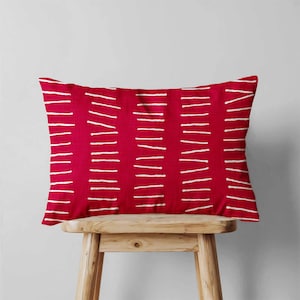Peut inclure: Un coussin rectangulaire dot&eacute; d'une base en tissu rouge vif avec un motif r&eacute;p&eacute;titif de lignes horizontales blanches en pointill&eacute;s dispos&eacute;es en colonnes verticales sur toute la surface, cr&eacute;ant un aspect textur&eacute; et graphique.