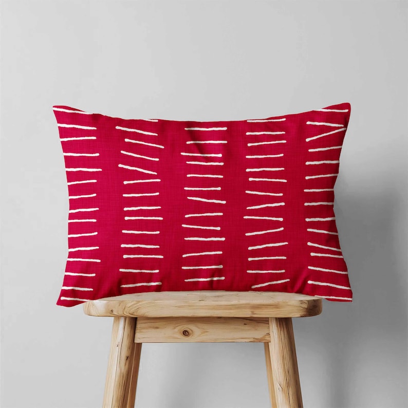Peut inclure: Un coussin rectangulaire dot&eacute; d'une base en tissu rouge vif avec un motif r&eacute;p&eacute;titif de lignes horizontales blanches en pointill&eacute;s dispos&eacute;es en colonnes verticales sur toute la surface, cr&eacute;ant un aspect textur&eacute; et graphique.
