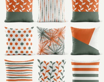 May include: A set of nine square throw pillows featuring various patterns in orange, dark green, and white. Designs include vertical leaf vines, dotted lines, polka dots, abstract starbursts, geometric triangles, and horizontal stripes in different widths.
