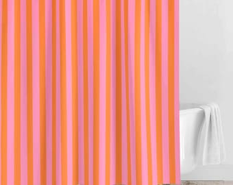 May include: A shower curtain featuring a repeating vertical striped pattern in alternating shades of bright orange and vibrant pink. The fabric hangs in soft, vertical folds, creating a consistent linear design across the entire surface.