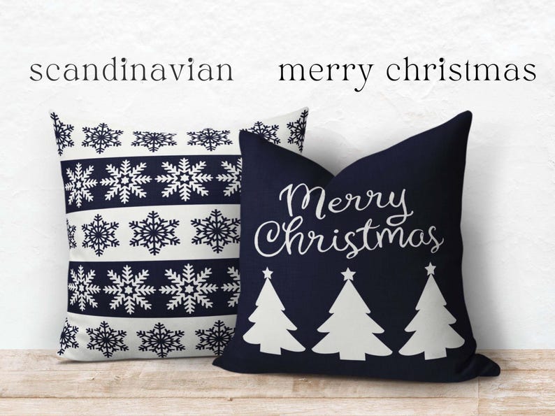 May include: Two square throw pillows. One pillow is white with dark blue horizontal stripes featuring snowflake patterns. The other pillow is dark blue with white text reading Merry Christmas above three white stylized Christmas tree silhouettes.