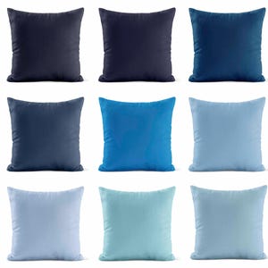 May include: Nine square throw pillows in various shades of blue, from deep navy to light sky blue. The pillows are arranged in a three-by-three grid, showcasing a range of colors and tones. Each pillow has a soft, plush appearance.