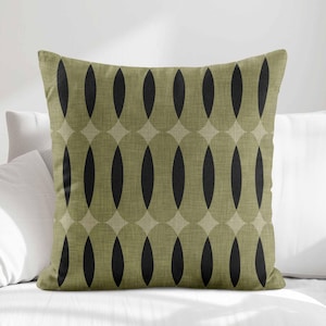 May include: Square decorative pillow with a geometric pattern. The pillow features a repeating design of black ovals set within olive green and tan interlocking shapes. The pillow has a textured appearance and is placed on a white surface.