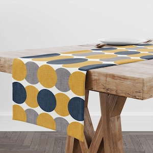 May include: A white ceramic mug with a black handle and the text "But First, Coffee" in a black, handwritten-style font. The mug is on a white surface.