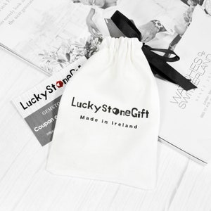 May include: A white drawstring bag with a black ribbon and the text "Lucky Stone Gift Made in Ireland".