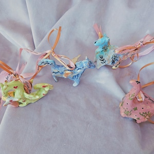 Puede incluir: Cuatro adornos de animales de cerámica con detalles pintados y cintas rosas, azules y verdes. Las cintas tienen el texto "Thanks for you" y "Thank you so much".