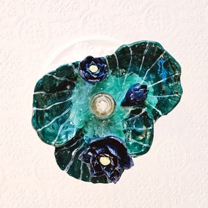 May include: A green and blue ceramic lotus flower ceiling light fixture with three blue flowers.
