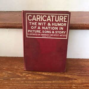 May include: A red hardcover book titled "Caricature: The Wit & Humor of a Nation in Picture, Song & Story" illustrated by America's Greatest Artists.  The book is a special edition.