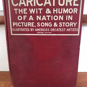 May include: A red book with the title "CARICATURE THE WIT & HUMOR OF A NATION IN PICTURE, SONG & STORY ILLUSTRATED BY AMERICA'S GREATEST ARTISTS SPECIAL EDITION"