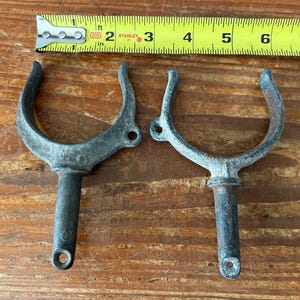 May include: Two metal boat cleat hooks with a silver finish. The hooks are about 6 inches long and have a rounded shape.