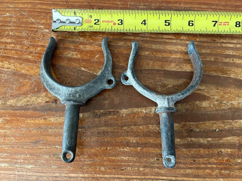 May include: Two metal boat cleat hooks with a silver finish. The hooks are about 6 inches long and have a rounded shape.
