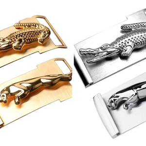 May include: Two metal belt buckles, one gold and one silver, each featuring an animal design. The gold buckle has a detailed alligator design, while the silver buckle has a detailed panther design.