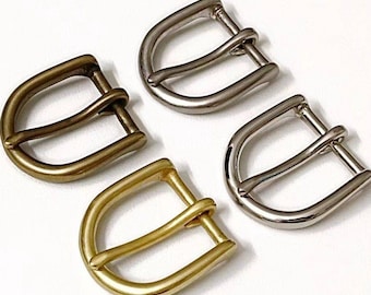 Könnte beinhalten: Vier Metall-Gürtelschnallen, zwei in Silber und zwei in Gold. Die Schnallen sind alle gleich groß und haben die gleiche Form, mit einem Doppel-Schleifen-Design.
